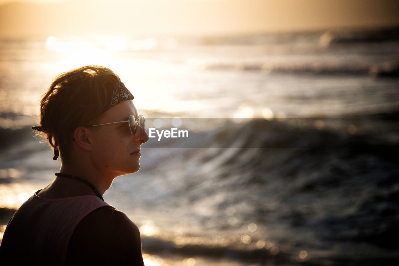 Portrait of man on beach against sky during sunset