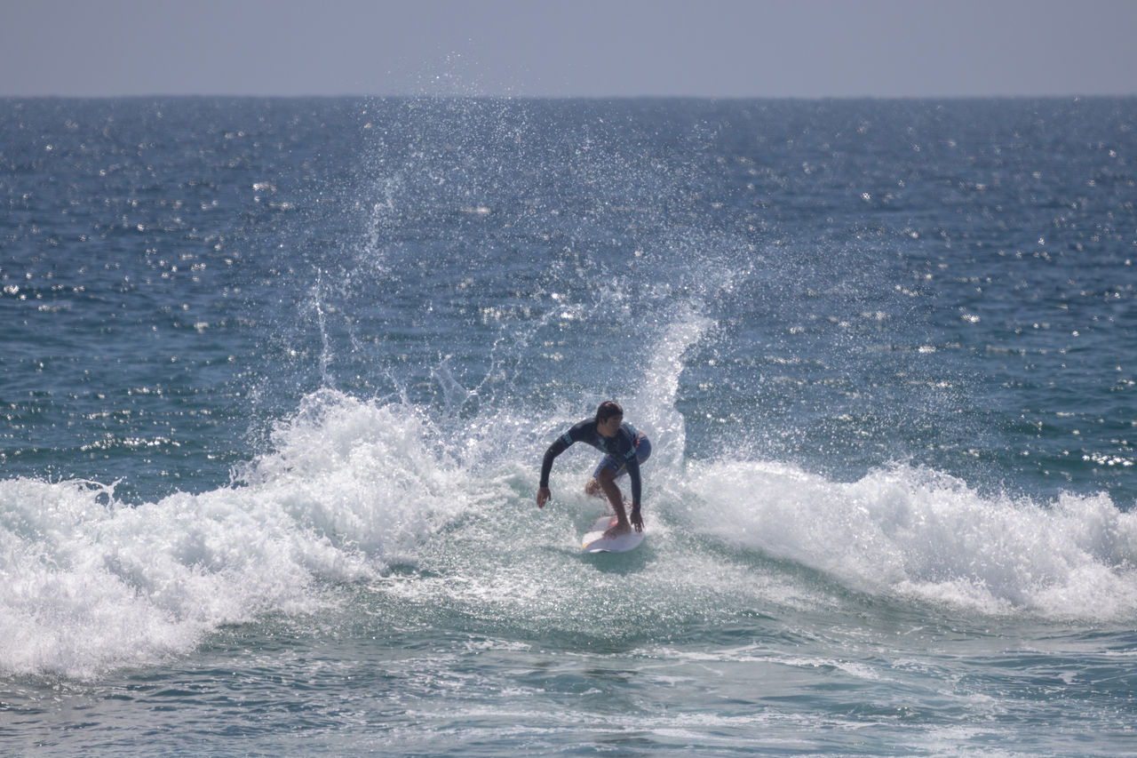 FULL LENGTH OF MAN SPLASHING WATER IN SEA