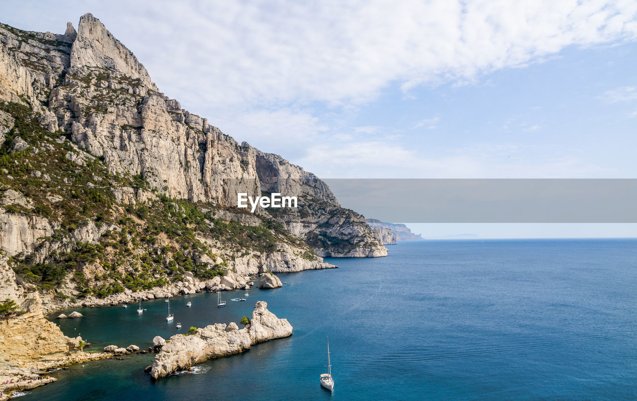 Scenic view of sea by rocky mountains against sky