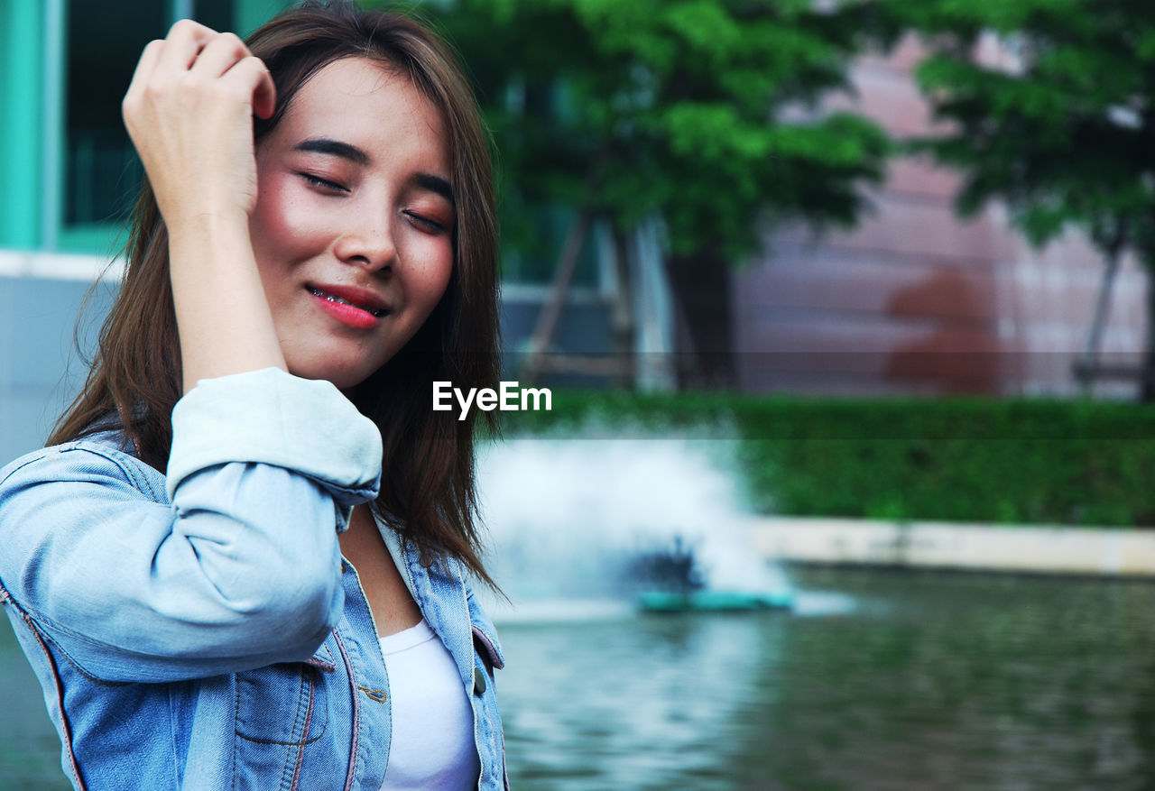 Beautiful young woman wiping sweat with tissue paper against fountain