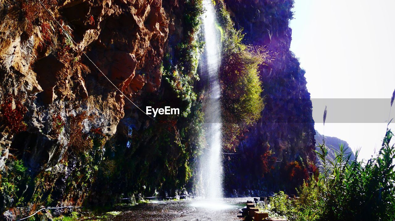 LOW ANGLE VIEW OF WATERFALL AGAINST TREES