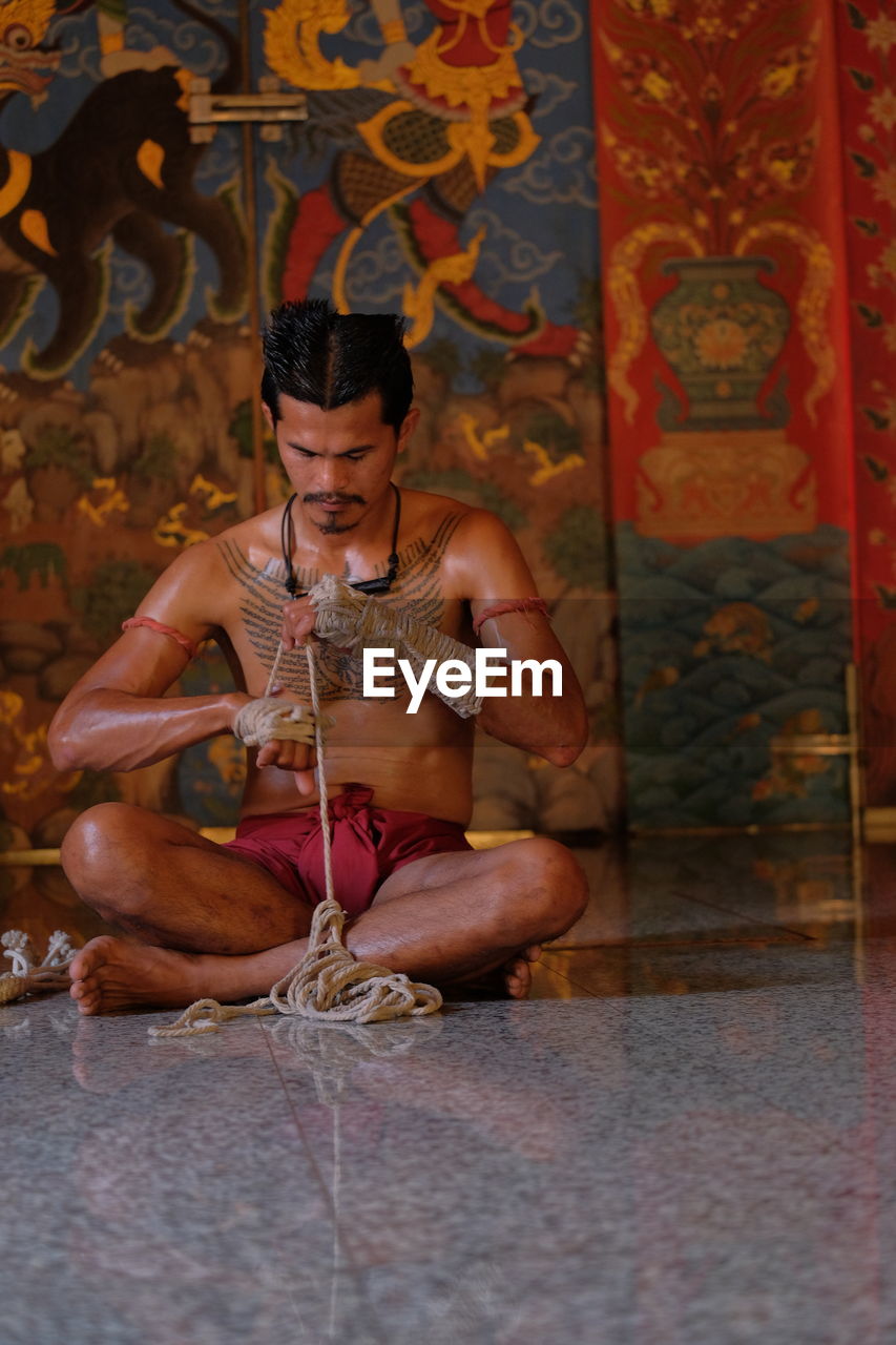 Full length of man working with rope while sitting in temple