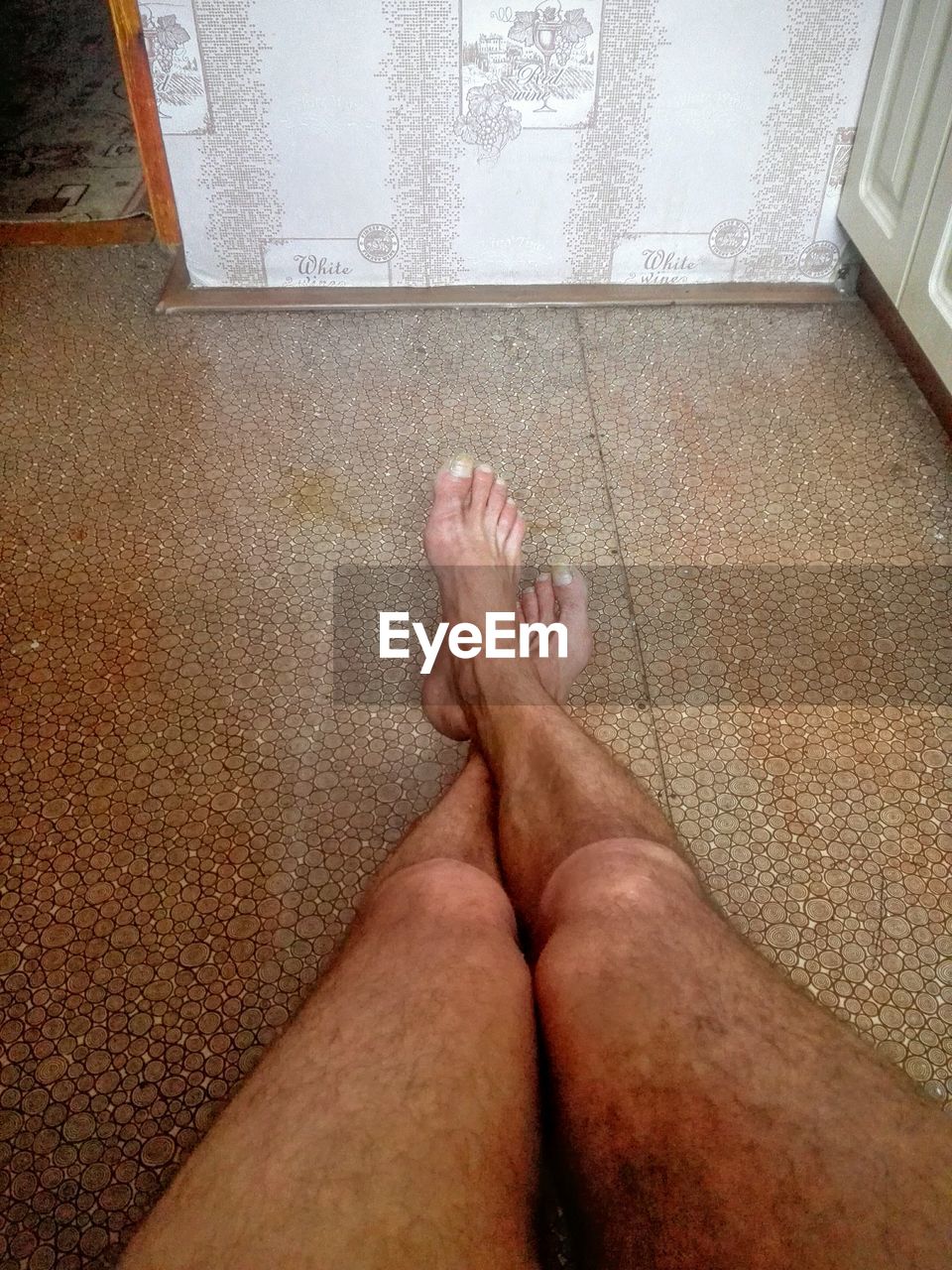 LOW SECTION OF WOMAN RELAXING ON TILED FLOOR