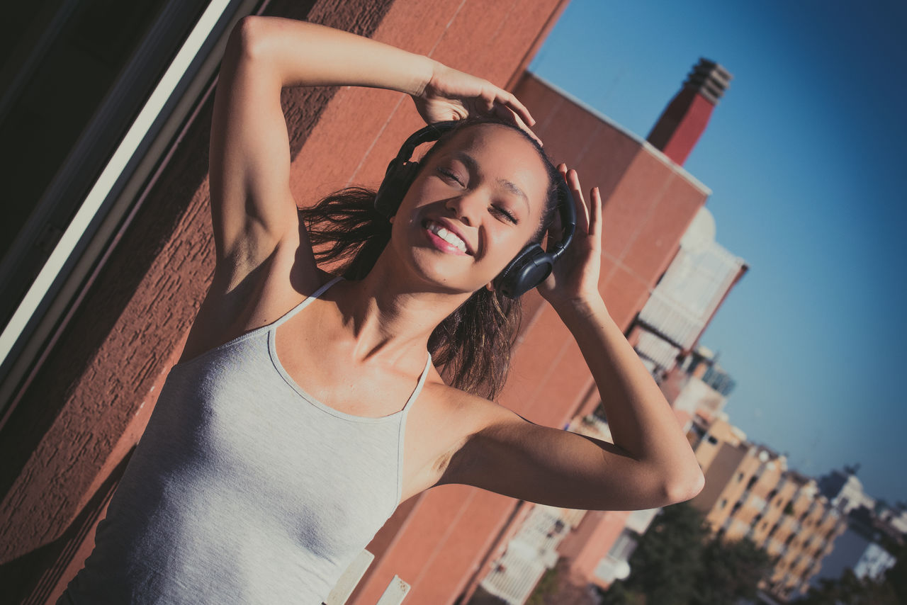 Woman listening music while standing in balcony