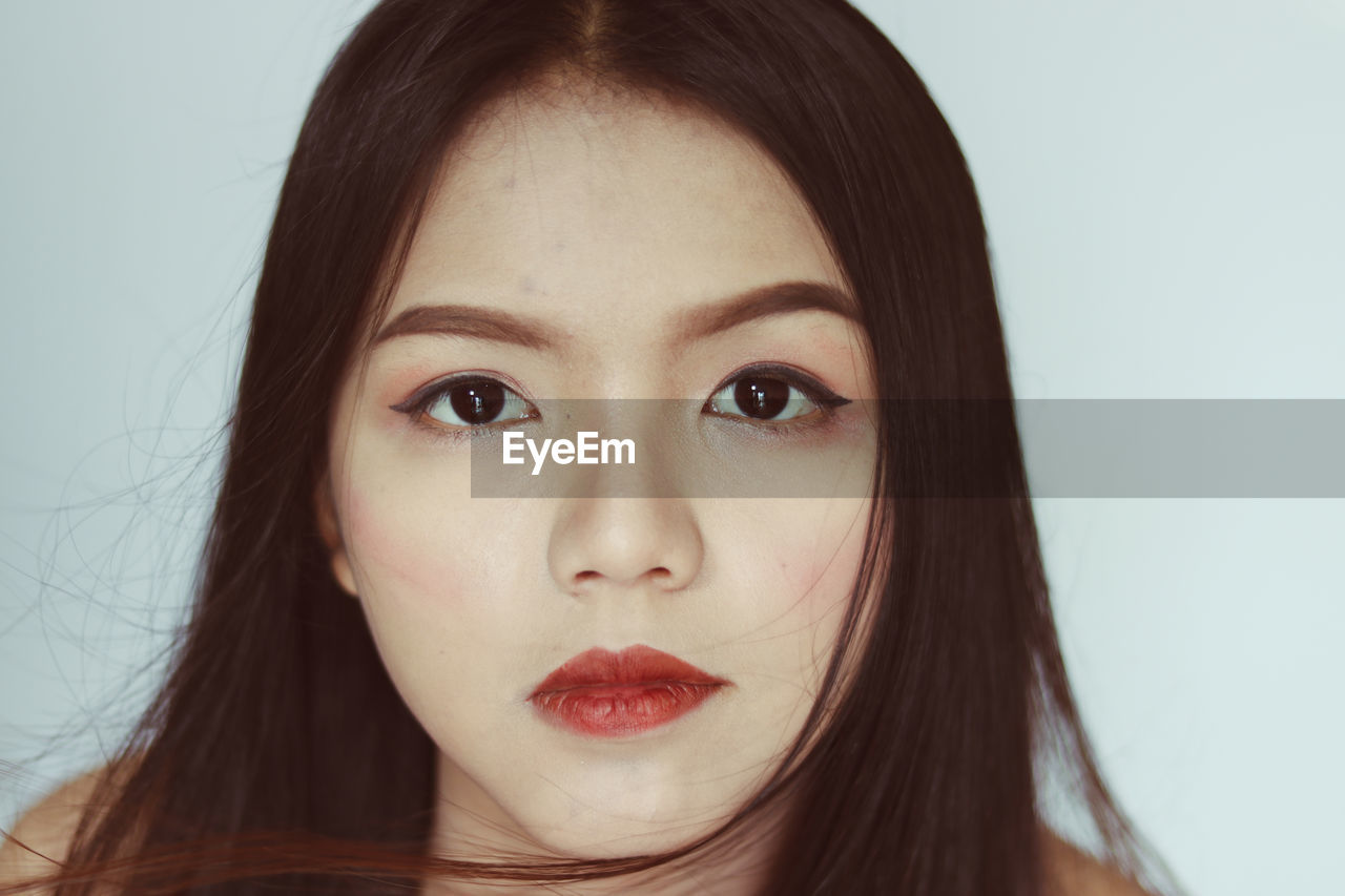 Close-up portrait of beautiful young woman against white background