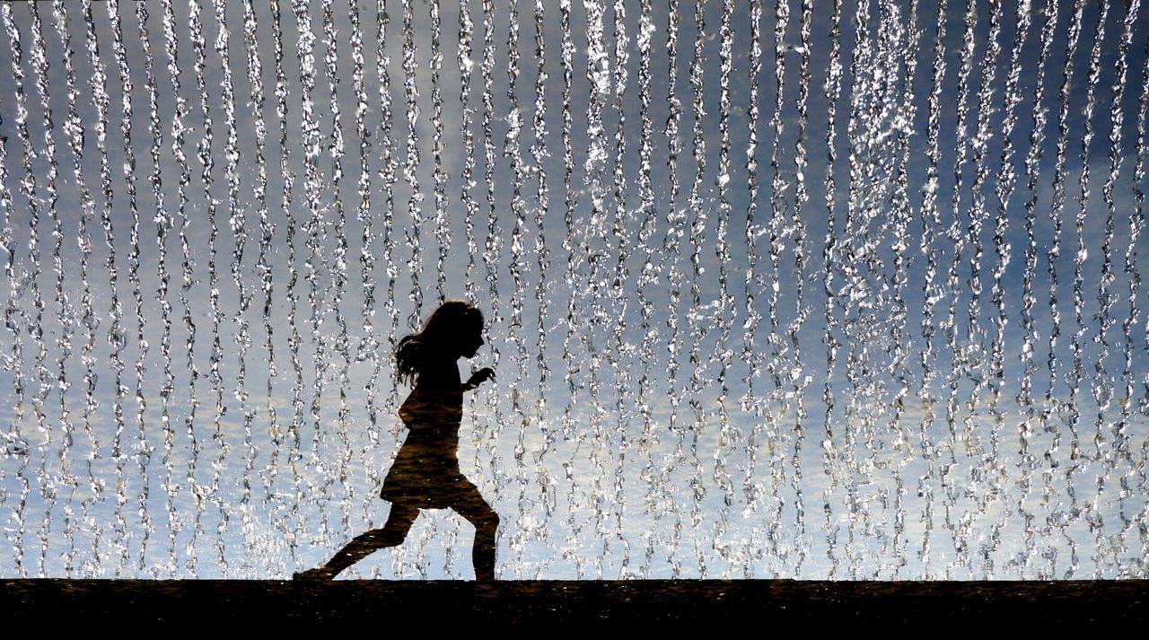Silhouette girl running against fountain