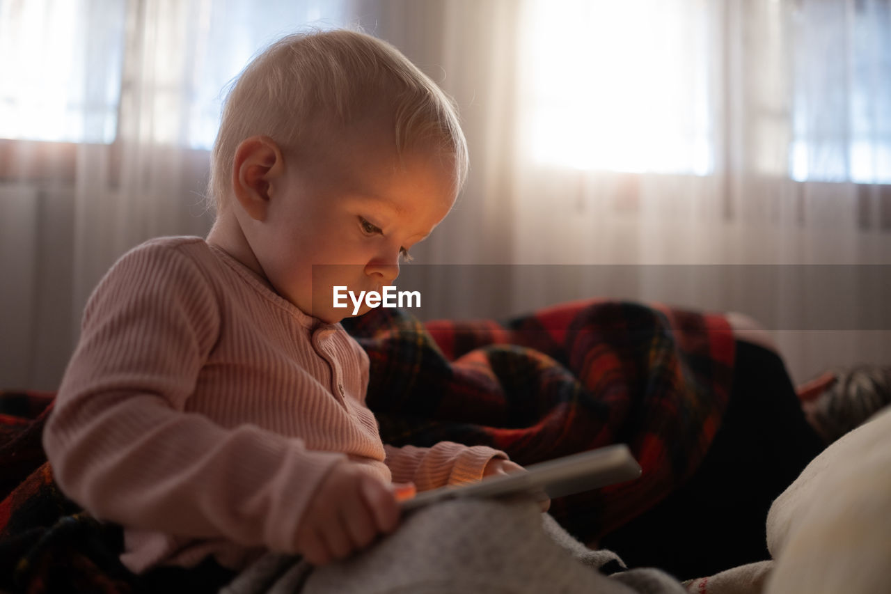 close-up of cute baby boy sitting on bed at home