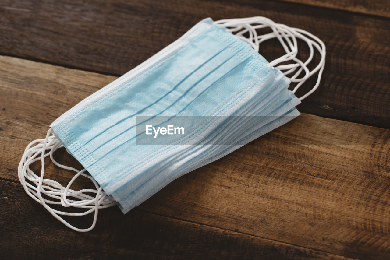 3 ply surgical mask stacked on wooden table. concept of medical, health care and virus protection