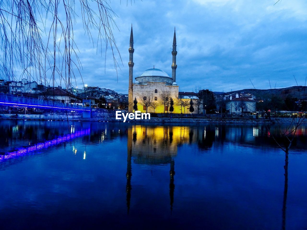 Reflection of mosque in lake against cloudy sky at dusk