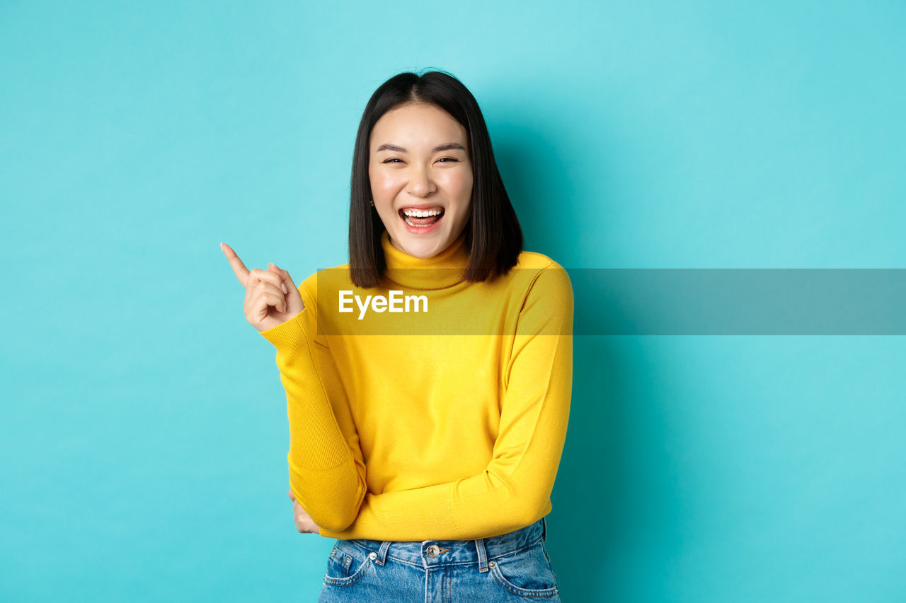 Smiling young woman standing against blue background