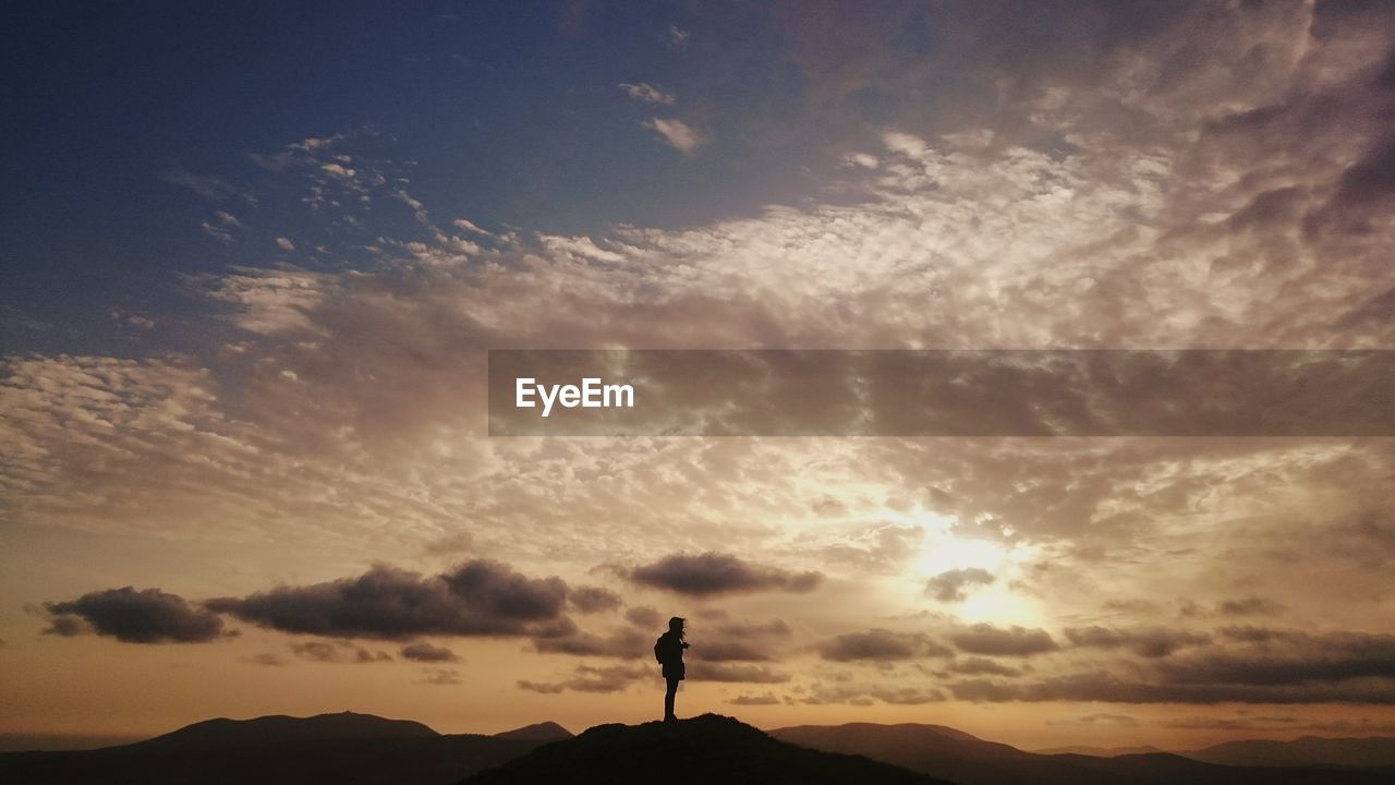 Silhouette of man on hill at sunset