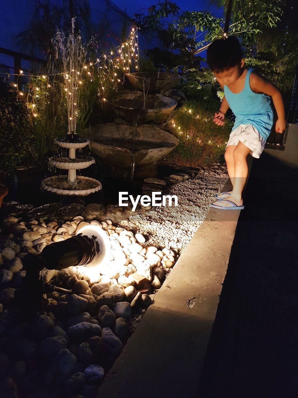 GIRL STANDING BY ROCK AT NIGHT