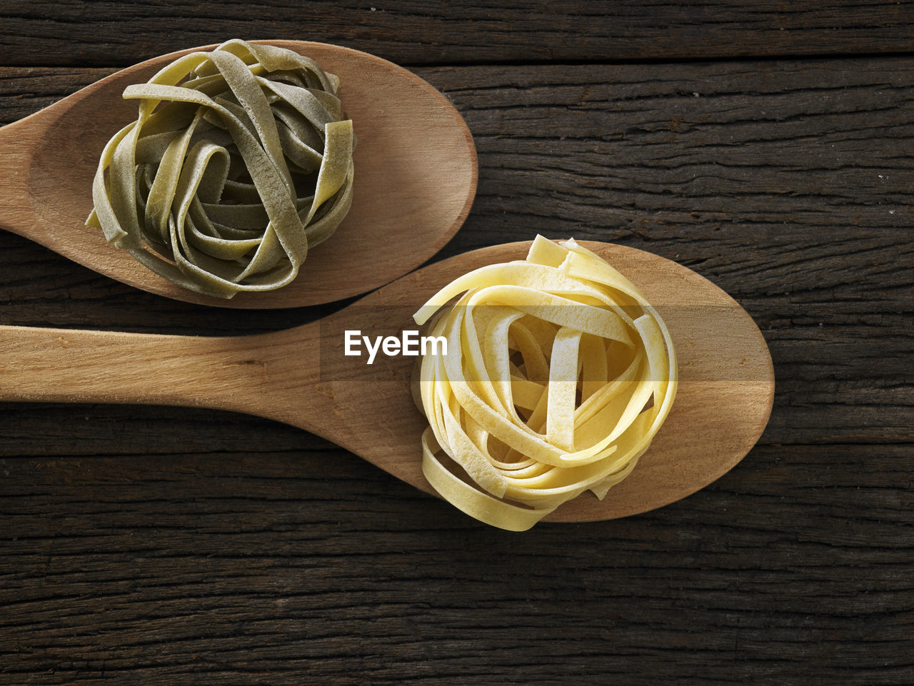 Close-up of tagliatelle pasta in wooden spoons on table