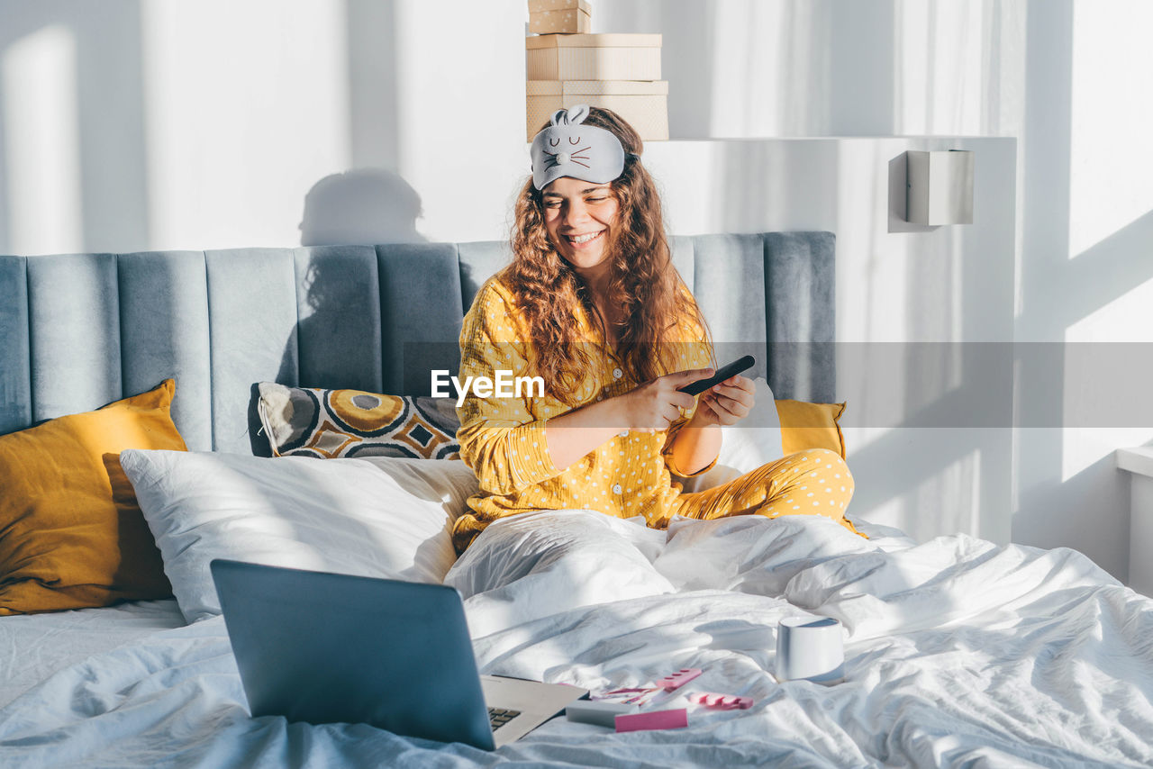 low section of woman sitting on bed