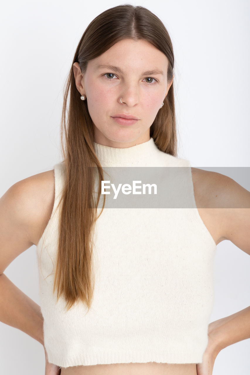 Portrait of young woman standing against white background