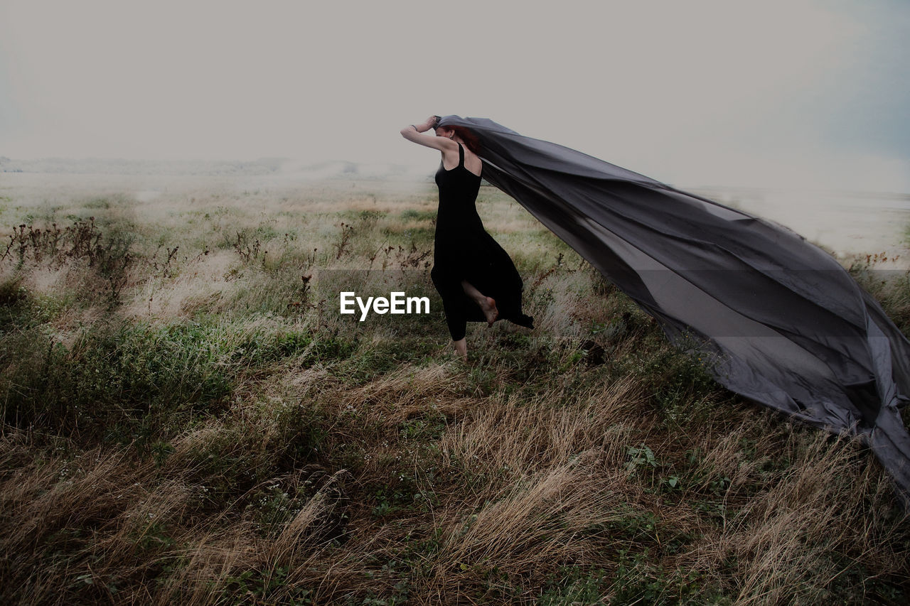 Woman holding gray shawl on grassy field