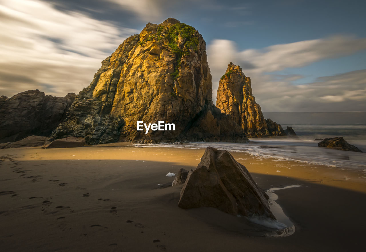 Rock formation on beach against sky