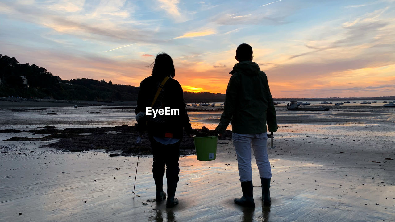 REAR VIEW OF WOMEN STANDING ON BEACH