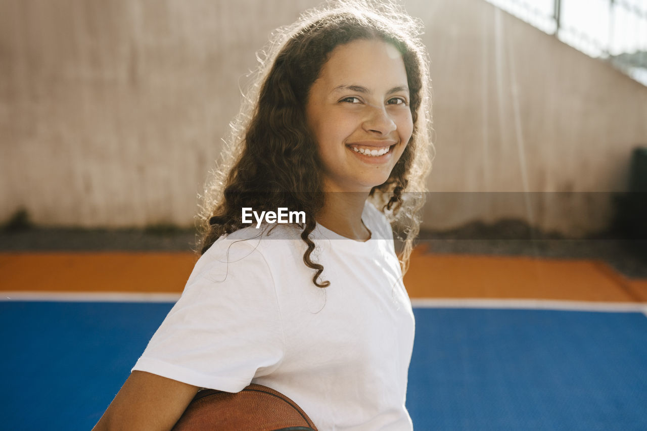 Portrait of happy pre-adolescent girl at sports court