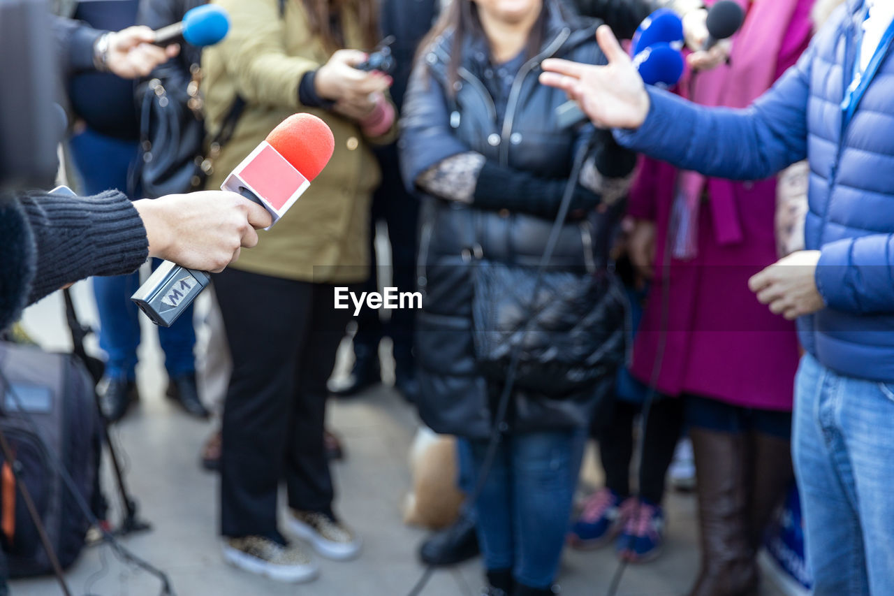 Reporters at news conference or media event, red microphone in the focus