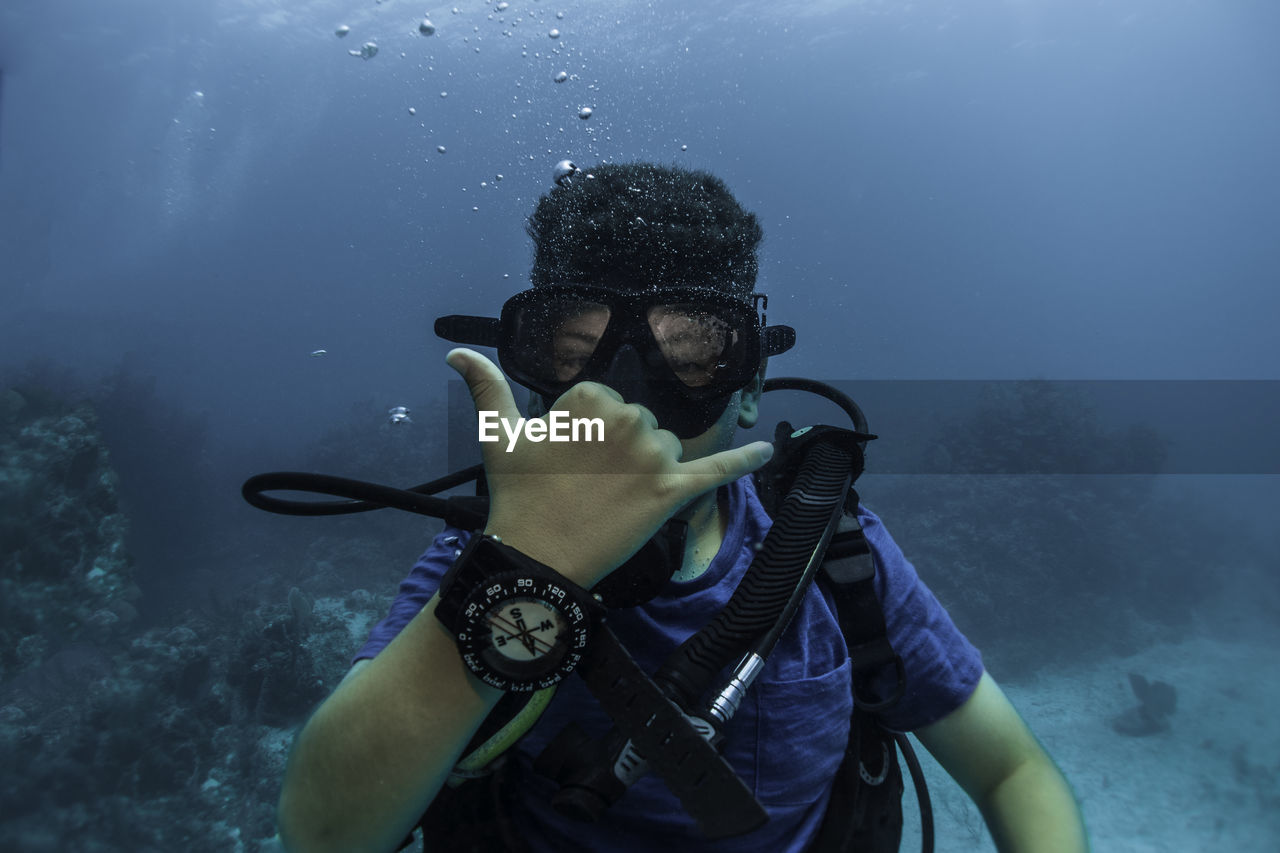 Young boy doing hand signal, doing scuba diving with a compass in the hand