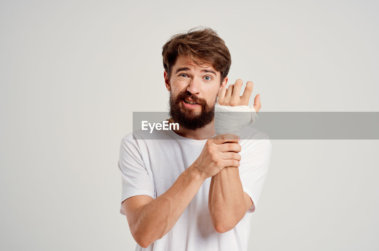 Portrait of man wearing bandage against white background