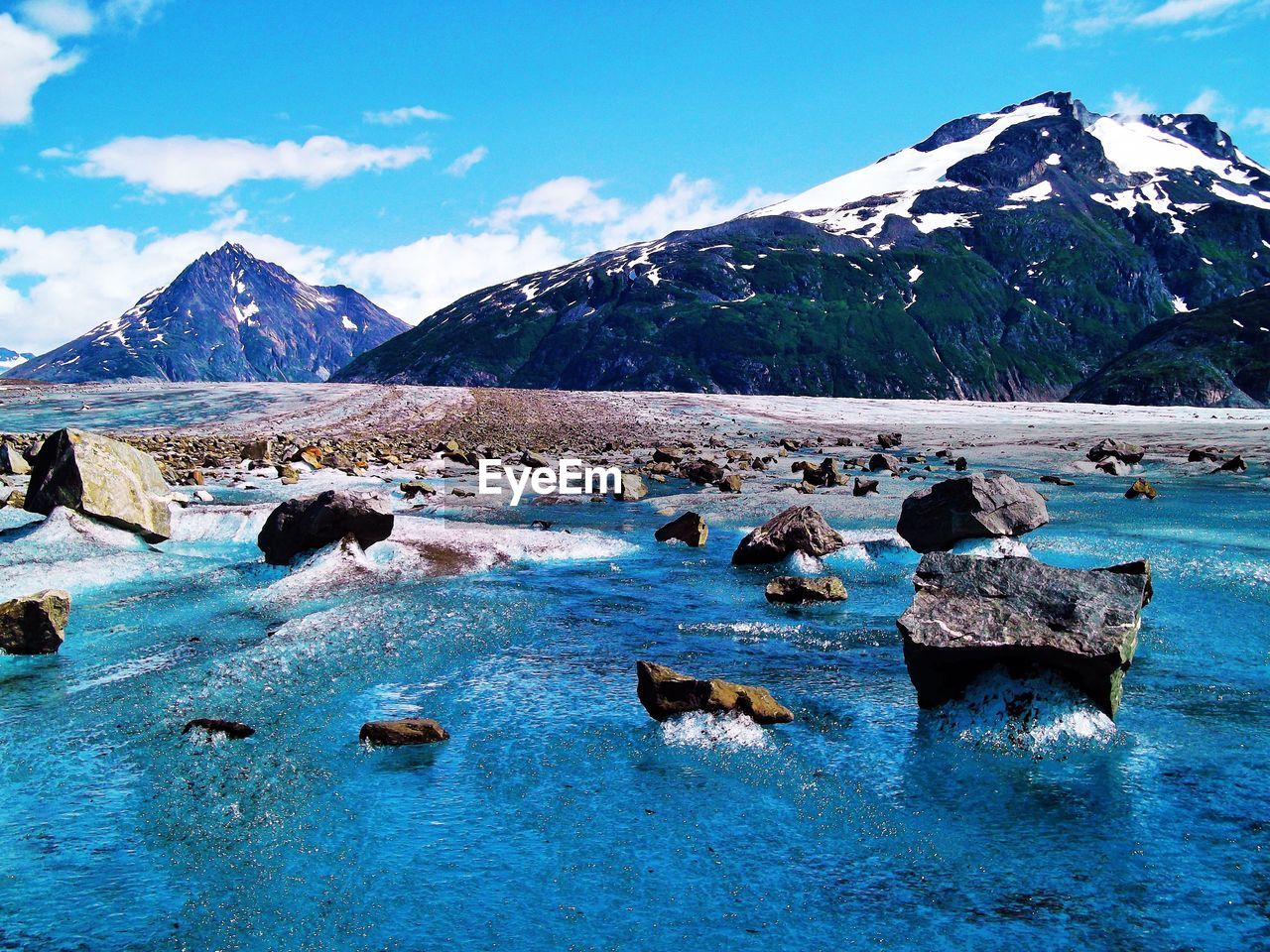 Scenic view of sea and snowcapped mountains against sky