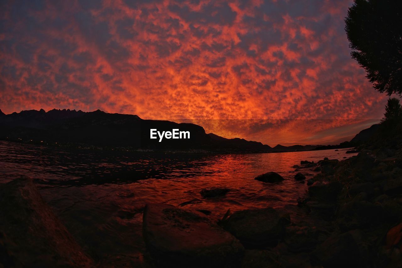 Scenic view of lake como against cloudy sky during sunset