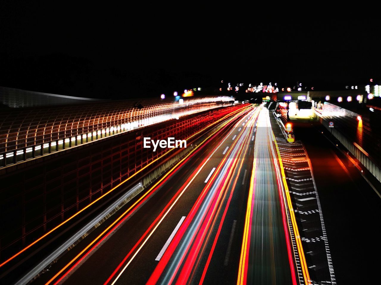 LIGHT TRAILS ON HIGHWAY AT NIGHT