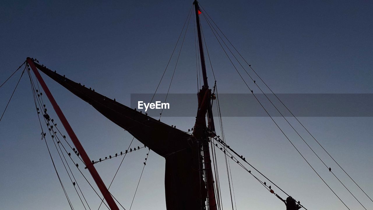 LOW ANGLE VIEW OF CRANES AGAINST CLEAR SKY