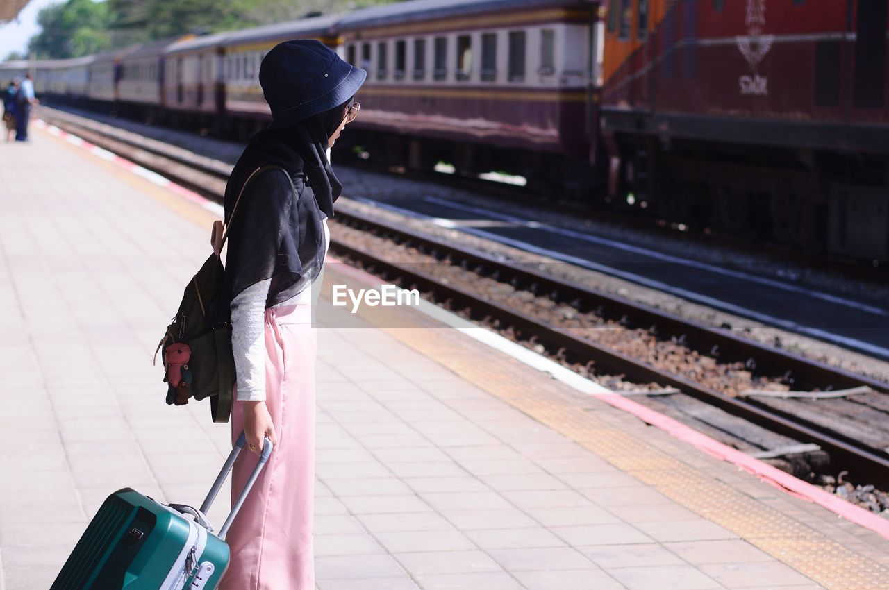 rear view of young woman walking on railroad station