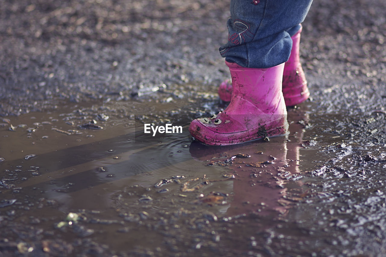 Low section of child playing in puddle