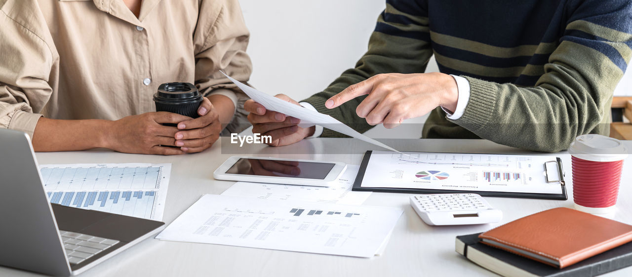 MIDSECTION OF COUPLE HOLDING MOBILE PHONE IN RESTAURANT