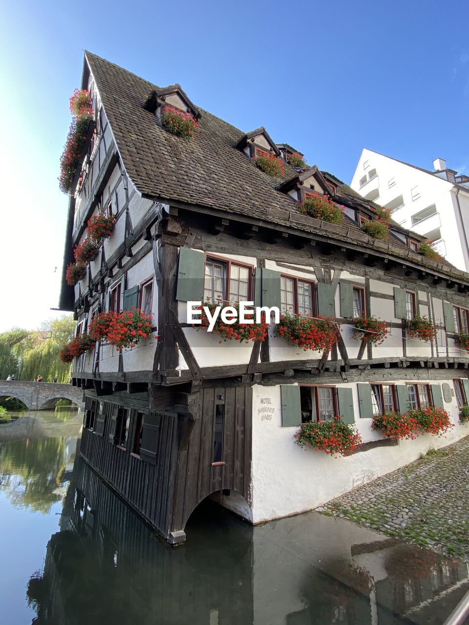 LOW ANGLE VIEW OF BUILDING BY RIVER AGAINST SKY