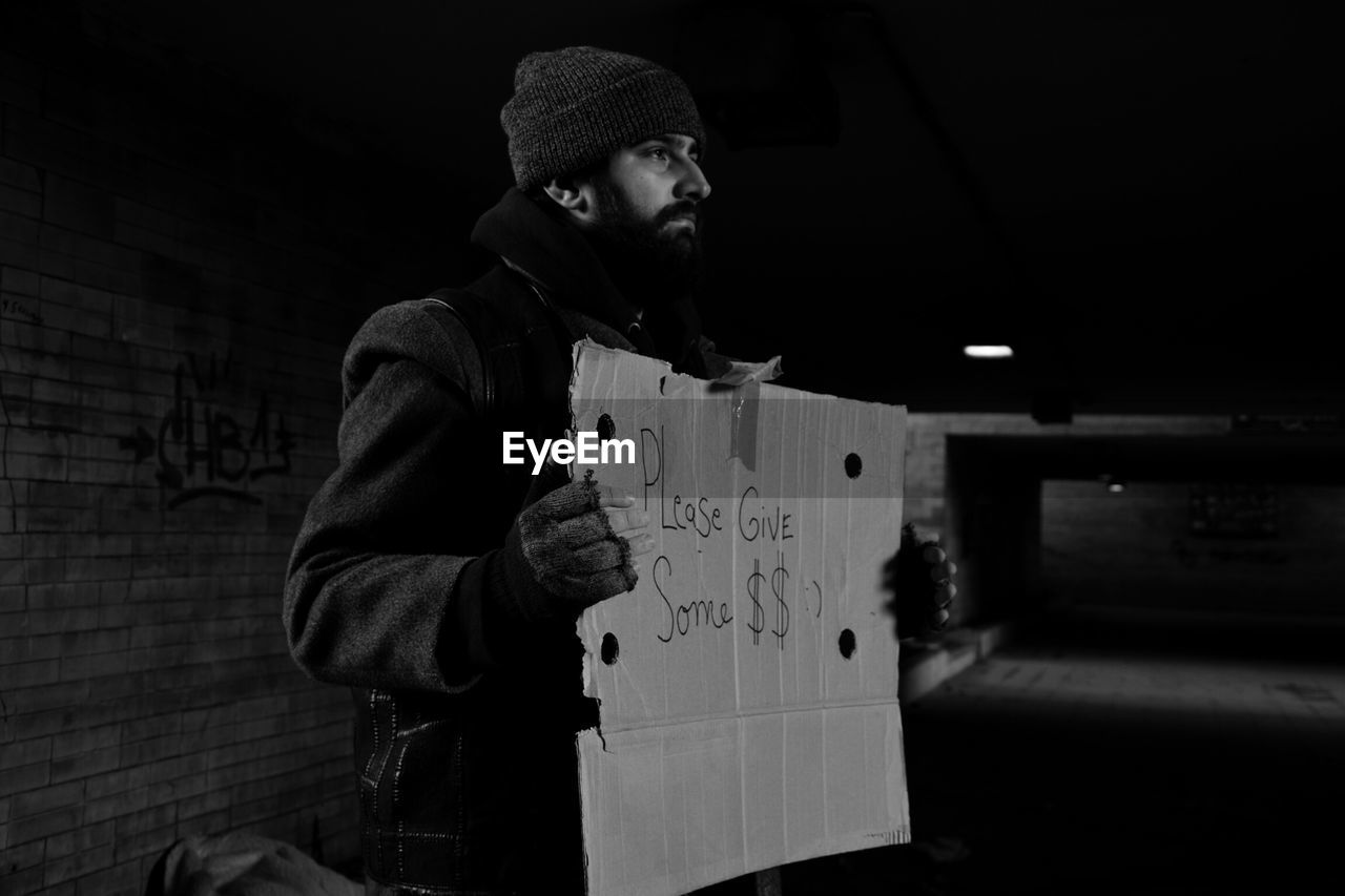 Homeless man holding banner with text