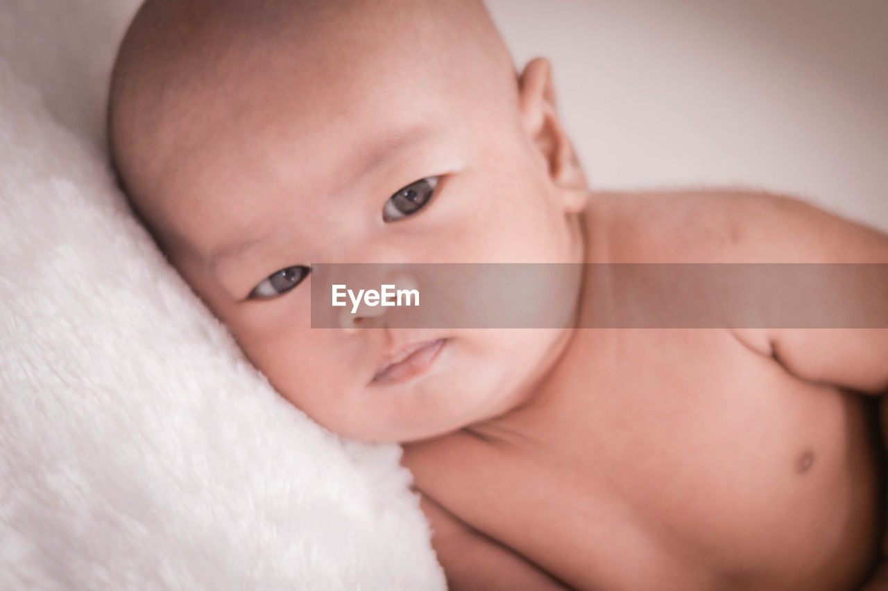 Close-up portrait of cute shirtless baby relaxing on fur