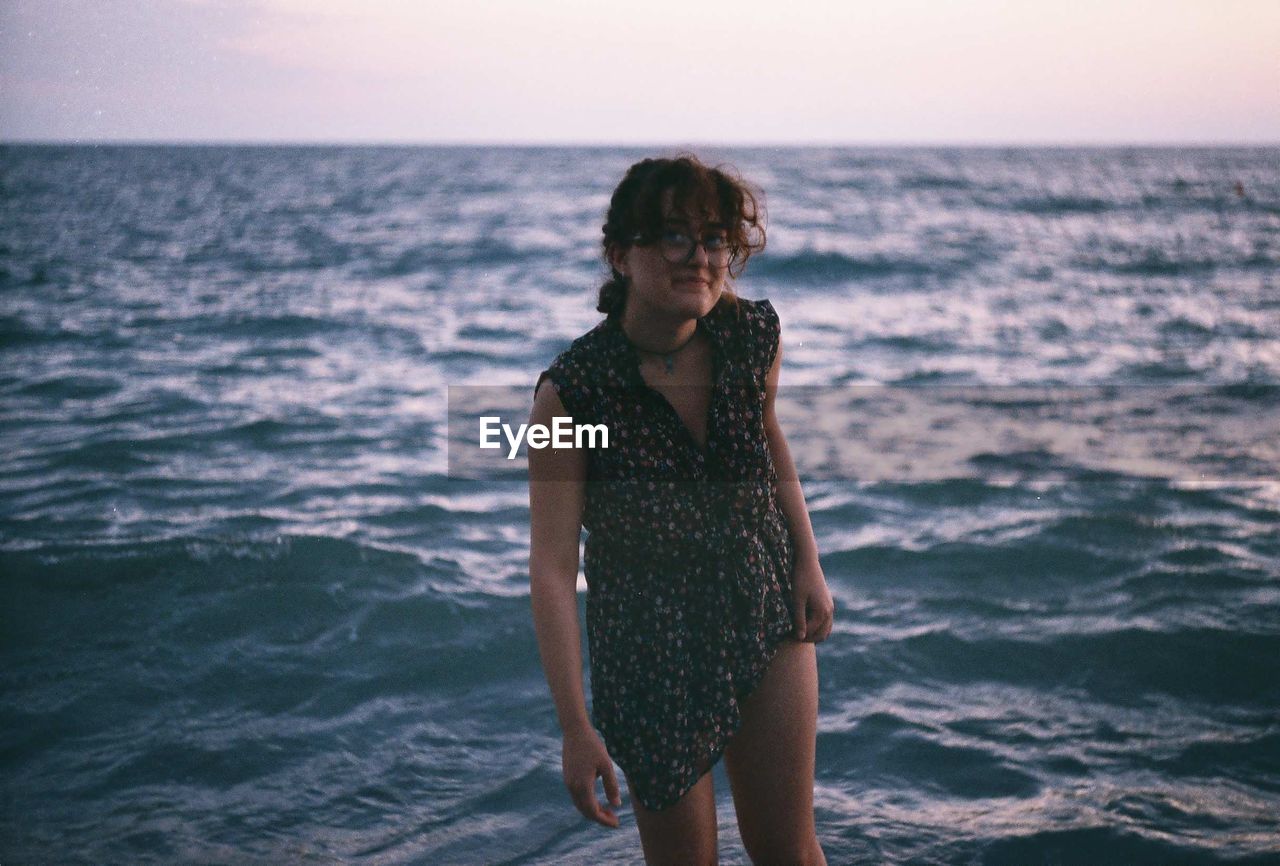 Portrait of young woman standing on shore at beach