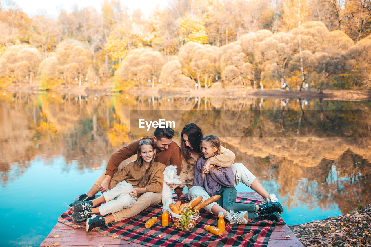 REAR VIEW OF A COUPLE SITTING ON LAKE