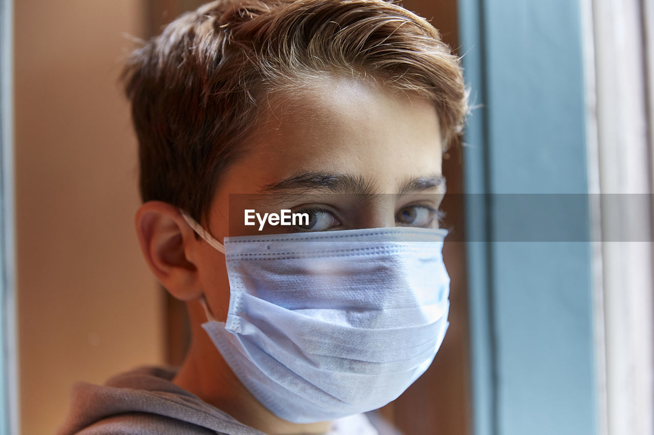 Close-up portrait of boy wearing mask at home