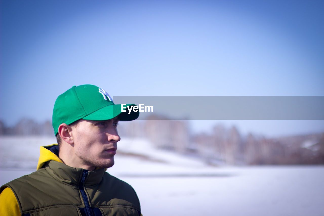 Close-up of young man wearing cap looking away