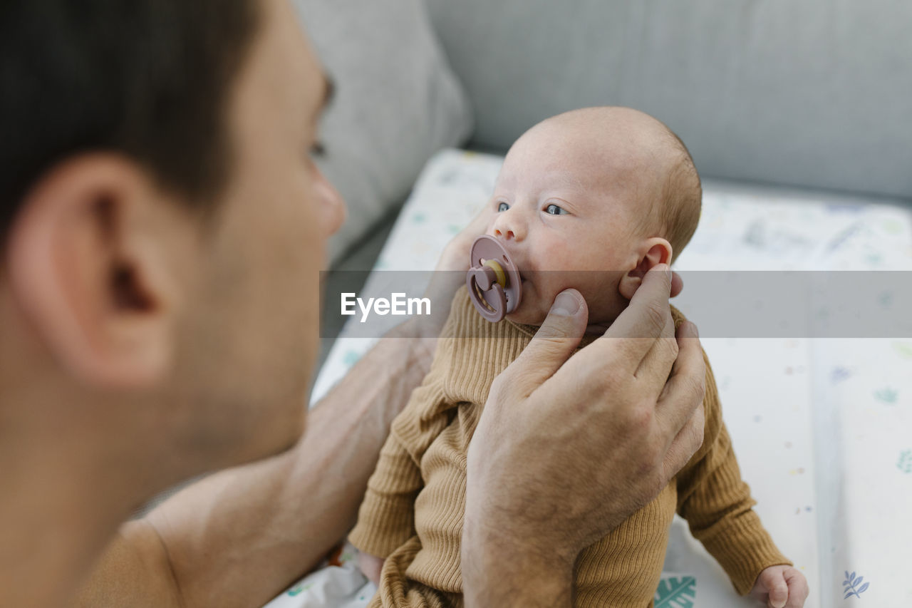 Man holding baby with pacifier at home