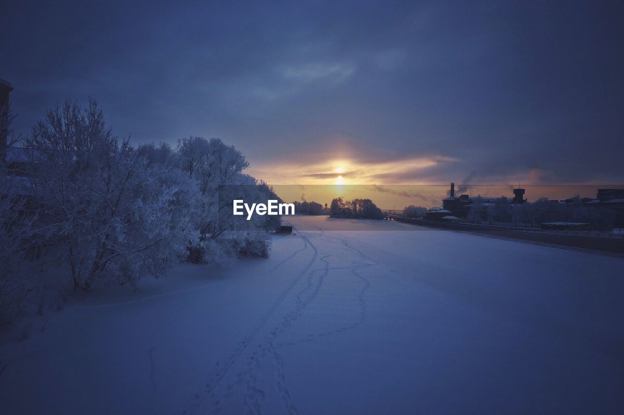 High angle view of snow covered field against cloudy sky during sunset