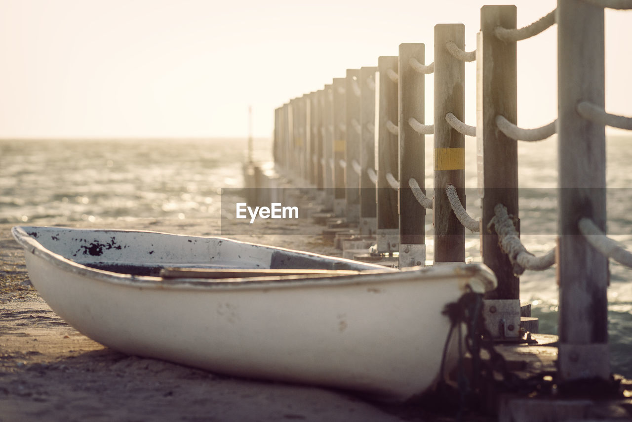 Boat moored at beach against clear sky during sunset