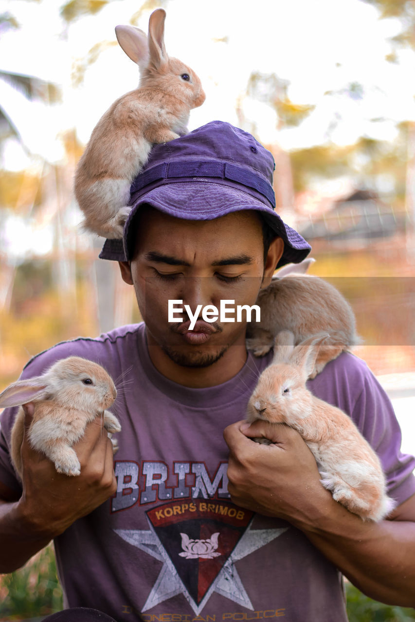 Young man puckering while holding rabbits