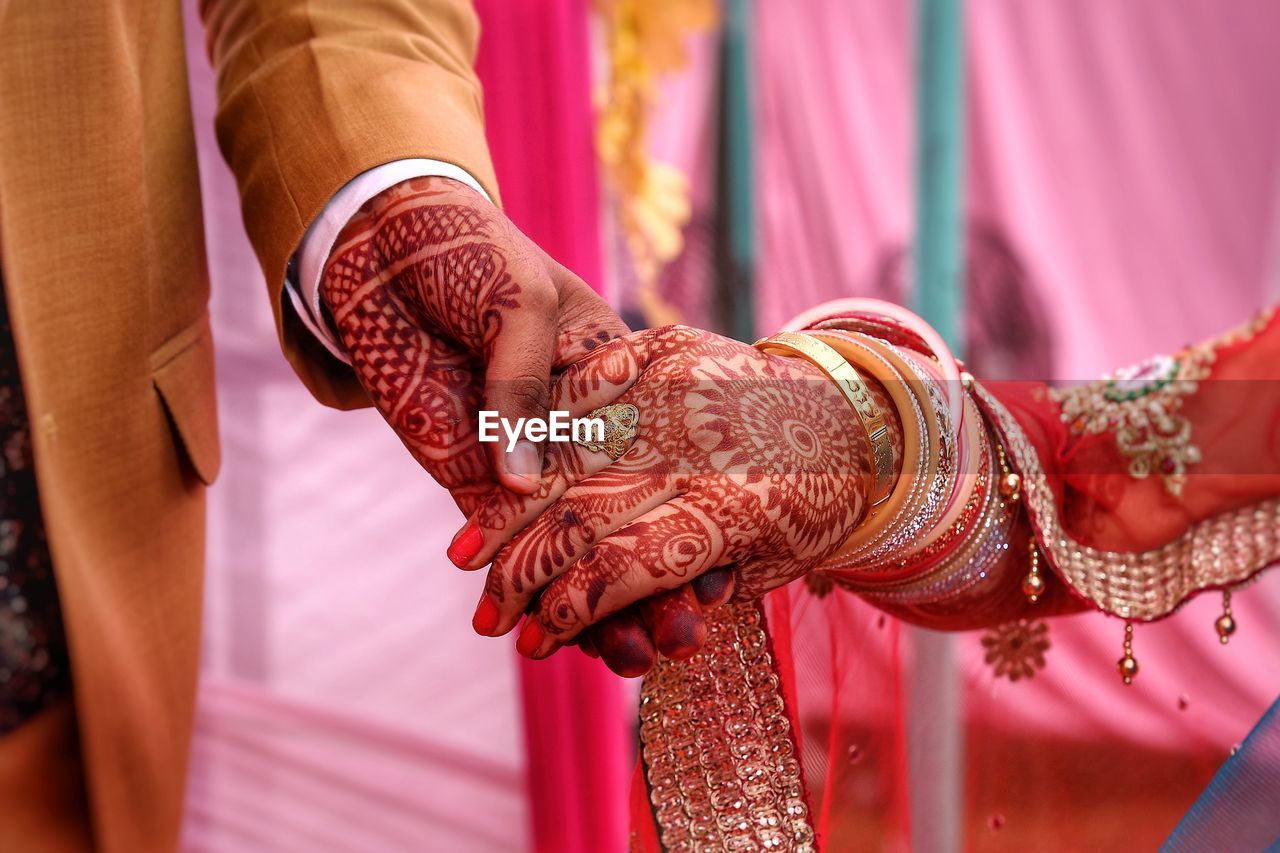 Cropped image of couple holding hands at wedding ceremony