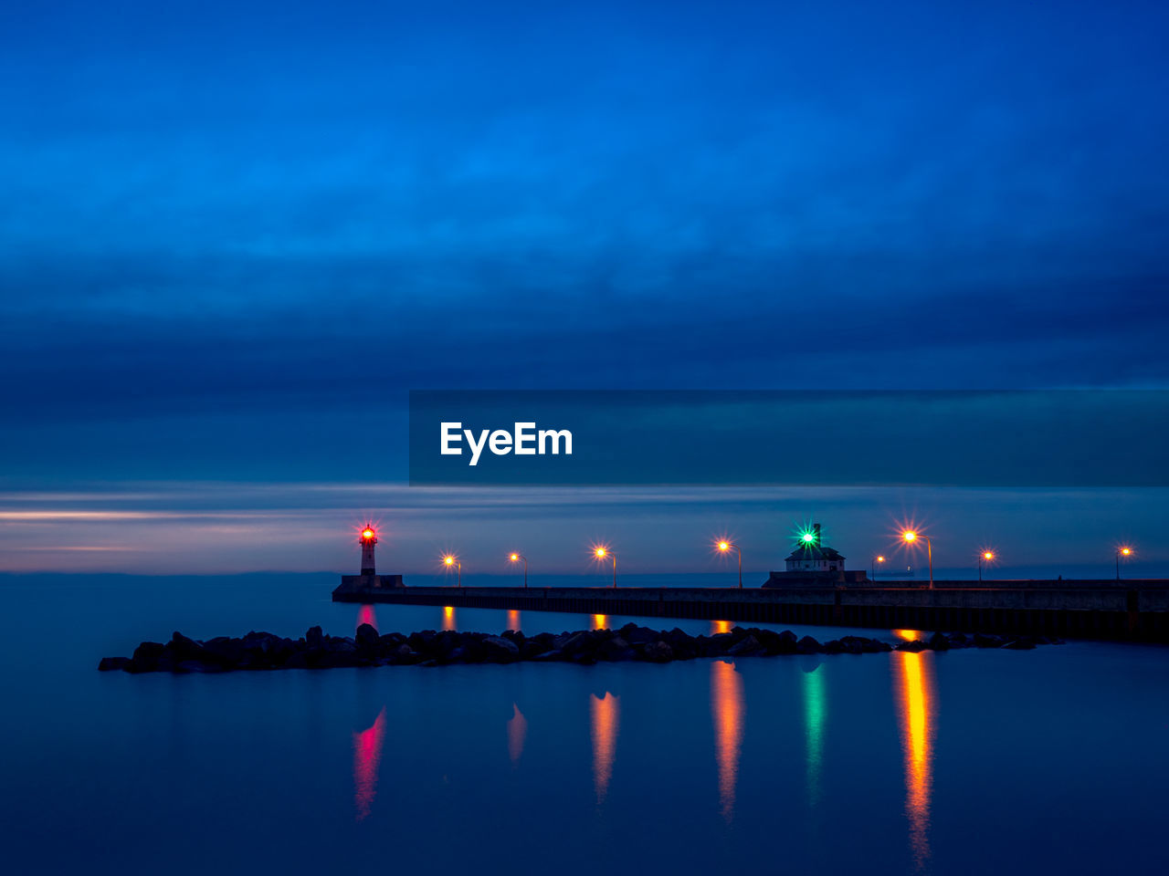 ILLUMINATED BRIDGE OVER SEA AGAINST BLUE SKY