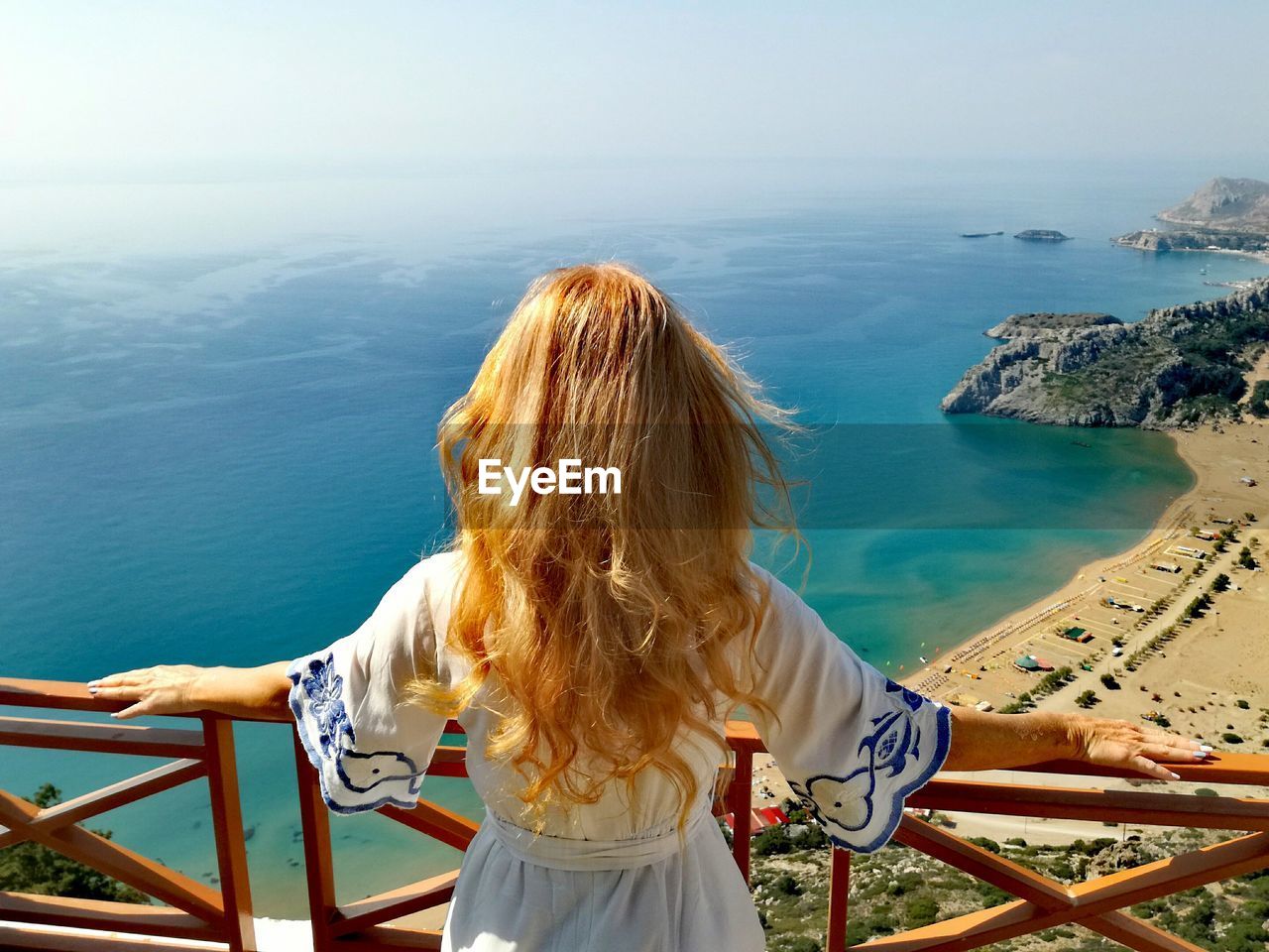 Rear view of woman with blond hair looking at sea during sunny day