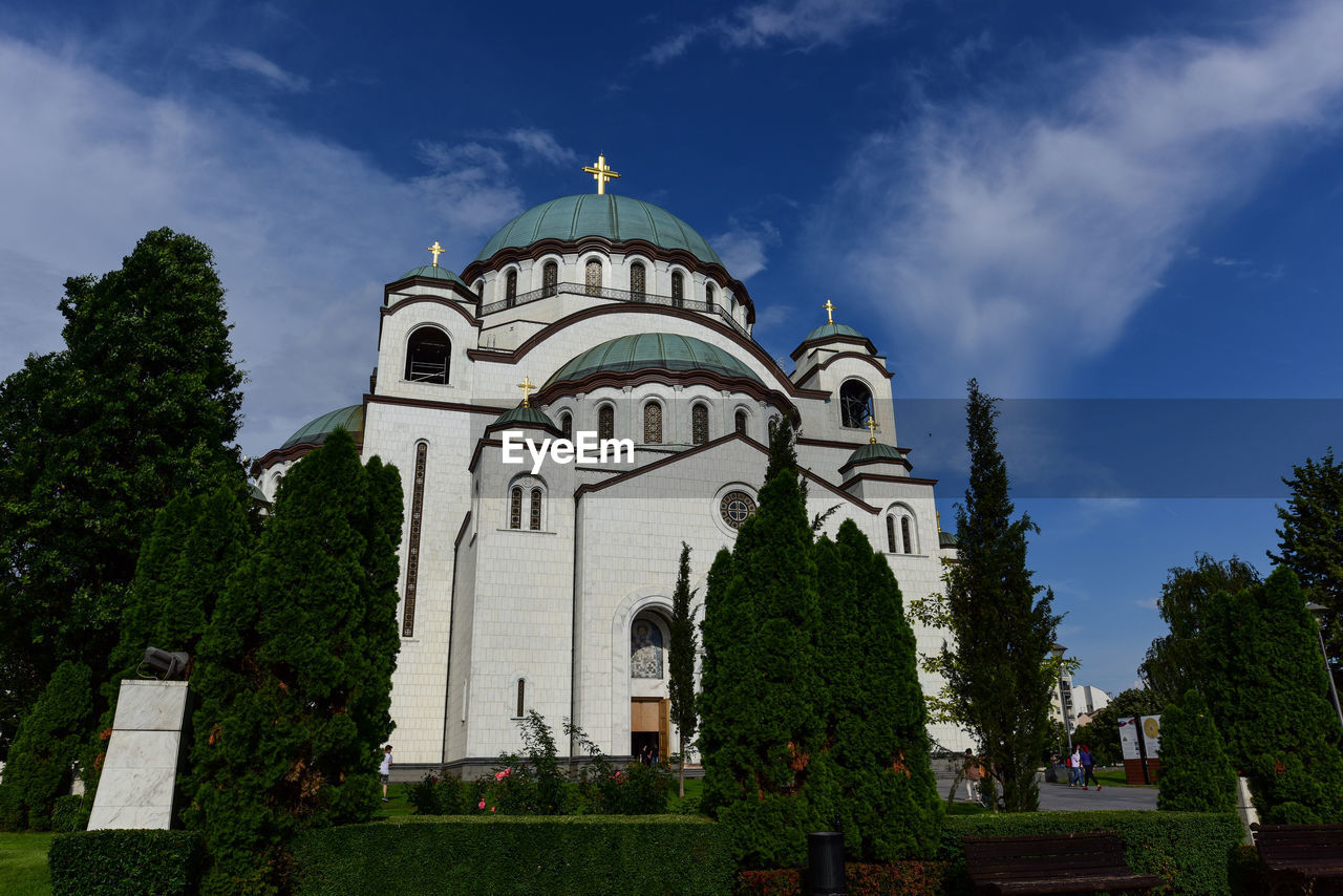 Low angle view of trees and church against sky