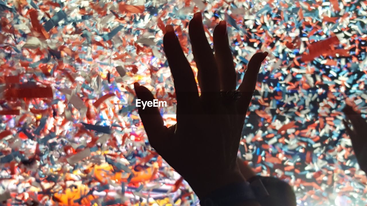 Cropped hand of woman against confetti at music concert