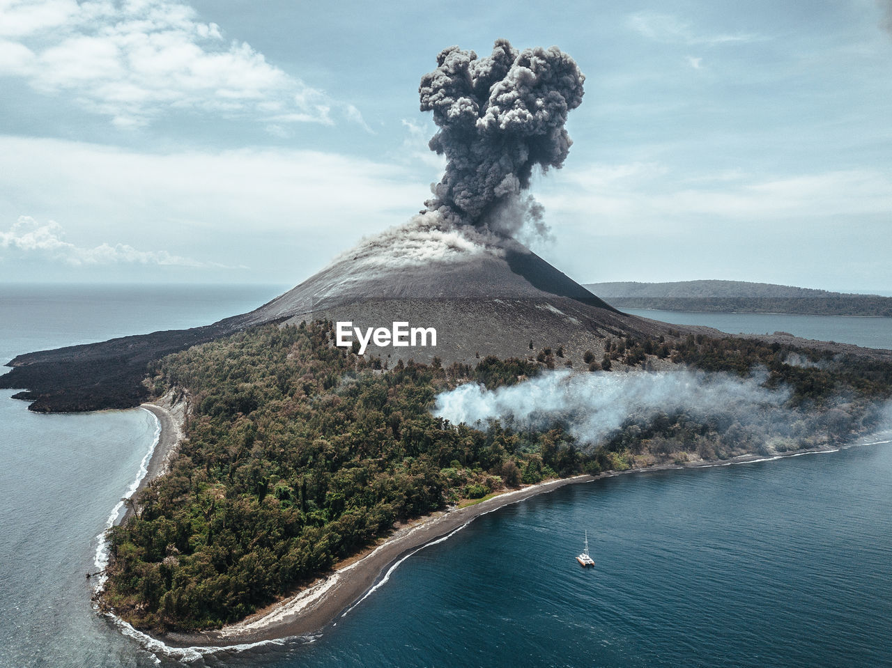 Volcano erupting on island against sky